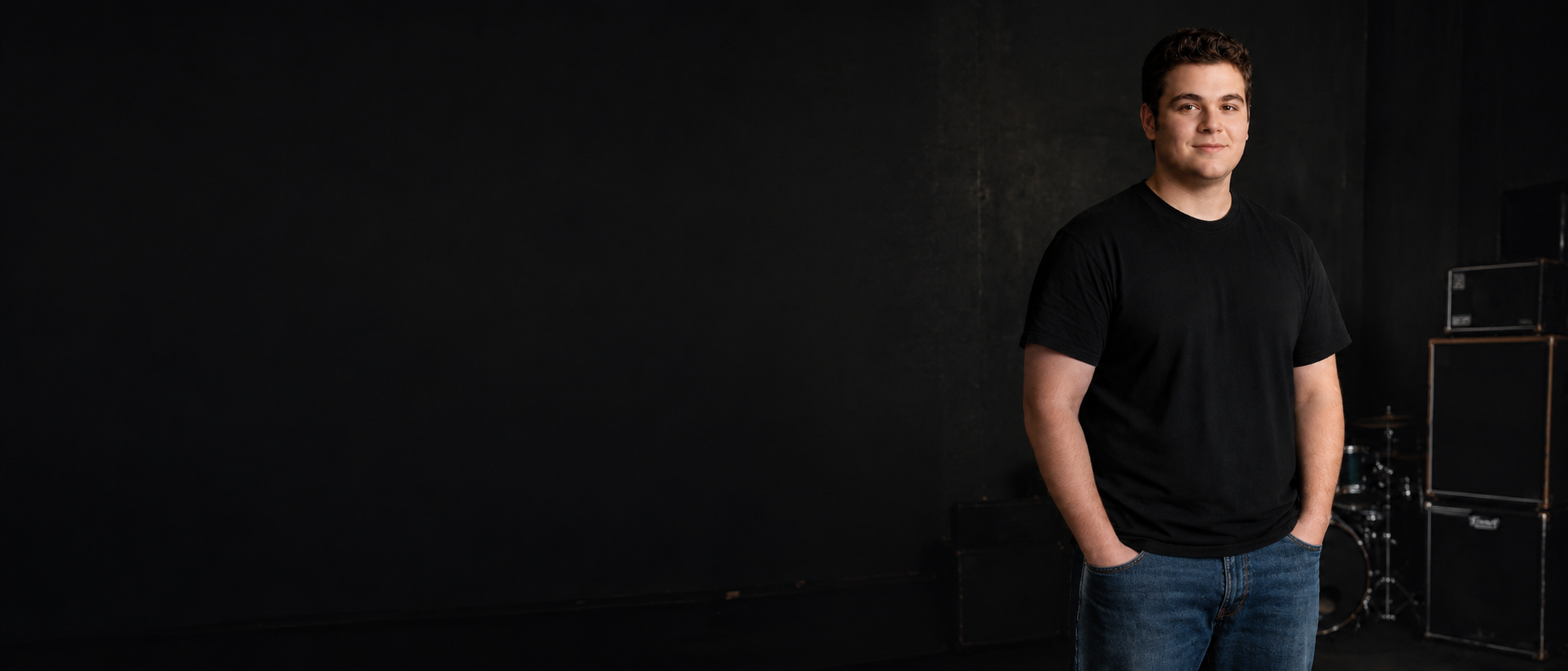 youthful looking youn man with light skin and dark short hair, dressed in a black tshirt.